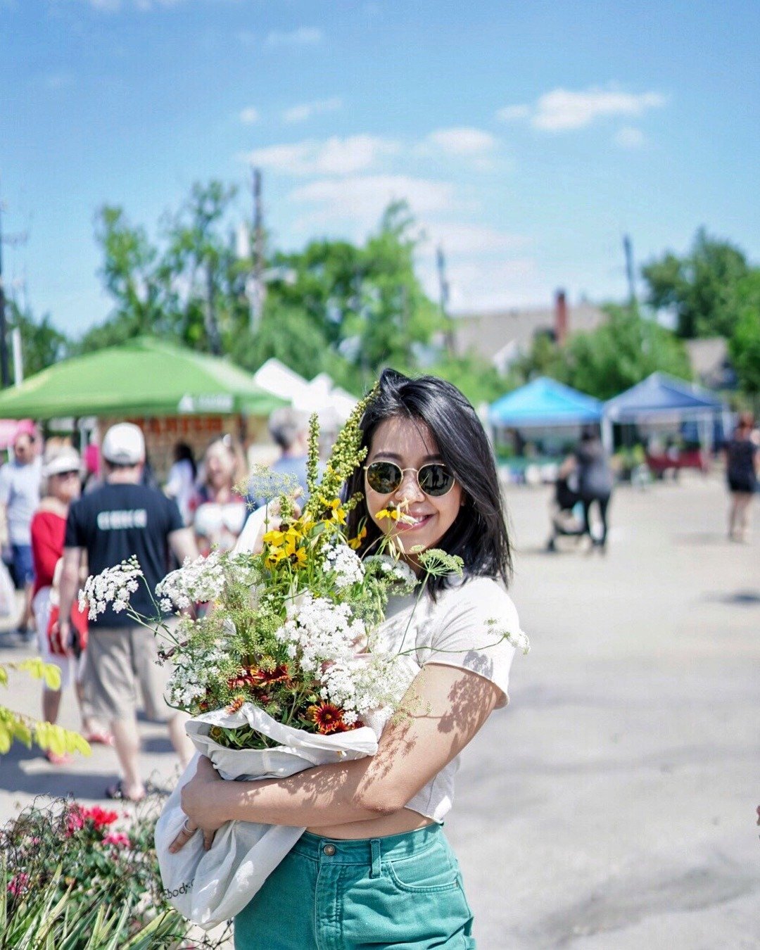 Photo of Ash Agnite holding a bouquet of wild flowers at the local farmers market